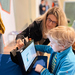 A woman shows a boy a tablet with a robot