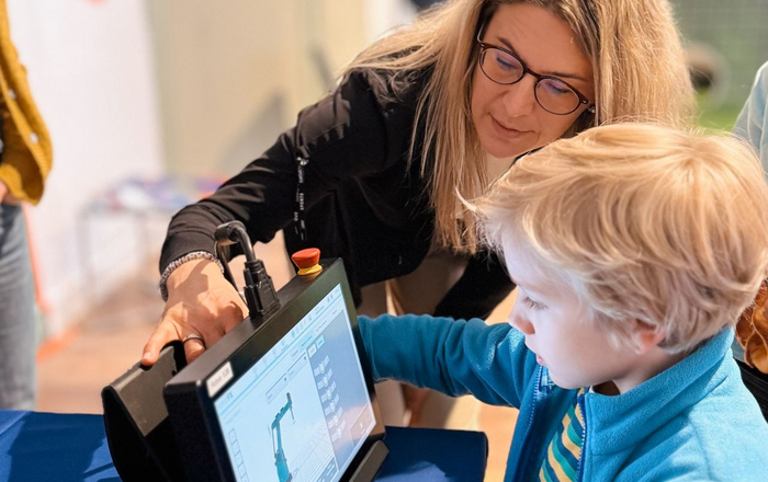 A woman shows a boy a tablet with a robot