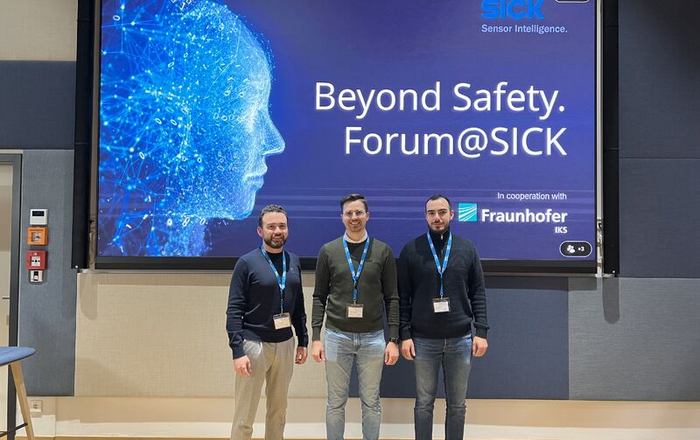  Drei Männer stehen vor einem Schild Beyond Safety Forum SICK