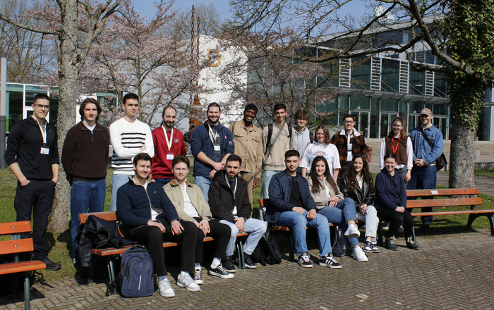 Gruppenfoto auf Bänken auf dem Campus in der Sonne